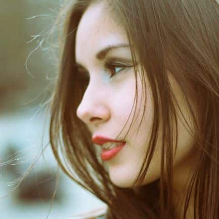 Stunning profile portrait of a young woman with long brown hair in a denim jacket.
