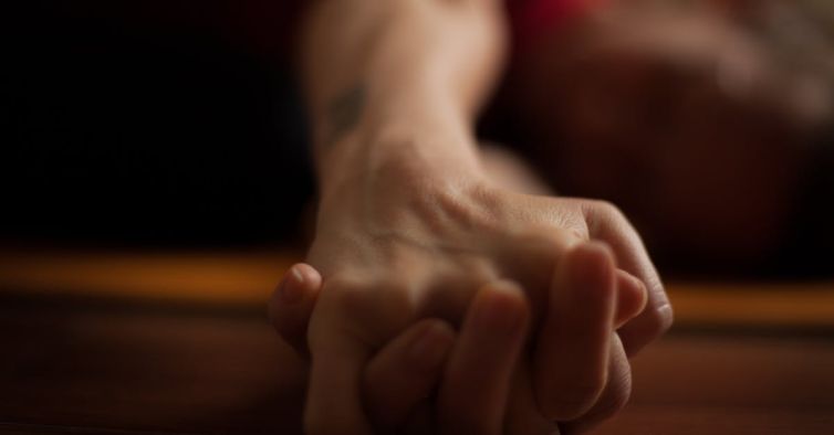 A close-up shot of two hands clasped together on a wooden surface, conveying intimacy and connection.
